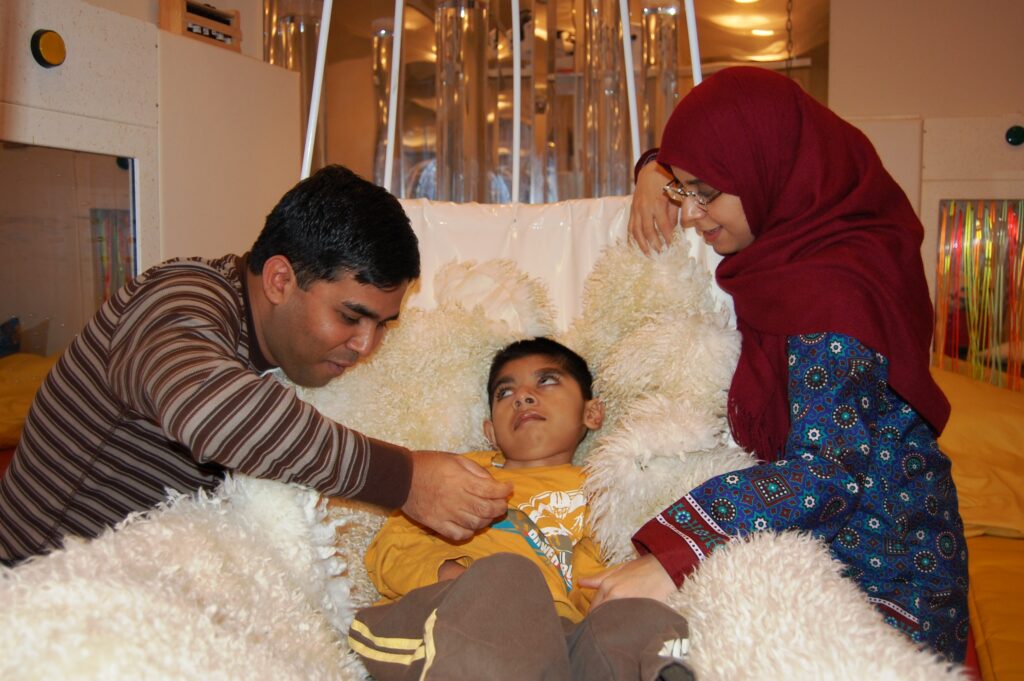 Child in a comfy swing with his parents caring for him.