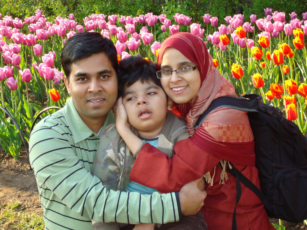 Parents hugging their son in front of a garden